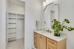 Bathroom featuring vanity and a walk in closet