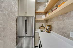Kitchen with freestanding refrigerator, wallpapered walls, light countertops, and open shelves