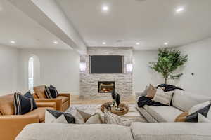 Living room with wood finished floors, arched walkways, recessed lighting, and a fireplace
