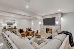 Living room with recessed lighting, a fireplace, arched walkways, and wood finished floors