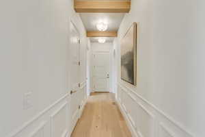Corridor featuring a decorative wall, light wood finished floors, and a wainscoted wall
