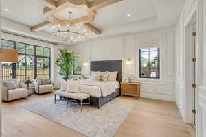 Bedroom with a decorative wall, coffered ceiling, a chandelier, light wood-style flooring, and beam ceiling