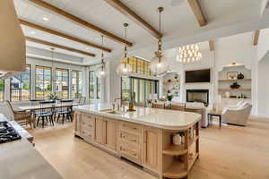 Kitchen with light brown cabinets, a sink, open shelves, light wood-type flooring, and beam ceiling