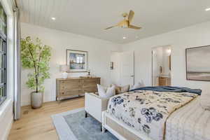 Bedroom featuring light wood finished floors, recessed lighting, multiple windows, connected bathroom, and a ceiling fan