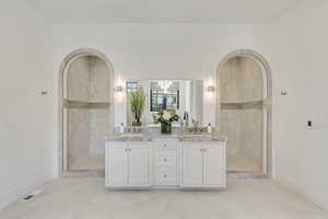 Bathroom featuring double vanity, a tile shower, and a chandelier