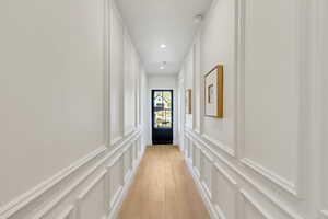 Hallway featuring a decorative wall, light wood-type flooring, and recessed lighting