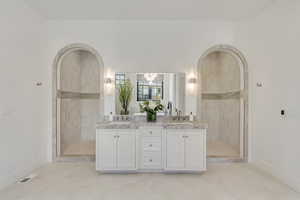 Bathroom featuring double vanity, a tile shower, and a chandelier