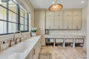 Kitchen featuring stone tile floors, light countertops, recessed lighting, pendant lighting, and cream cabinets