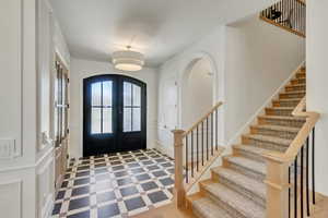 Entrance foyer with a decorative wall, french doors, stairs, and arched walkways