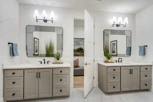 Full bath featuring marble finish floors and two vanities
