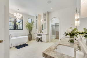 Bathroom with double vanity, a soaking tub, recessed lighting, a chandelier, and a walk in closet