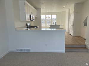 Kitchen featuring stove, stainless steel microwave, a chandelier, light countertops, and recessed lighting