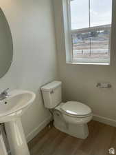 Half bath featuring toilet, wood finished floors, and baseboards