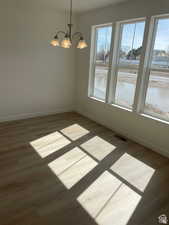 Empty room featuring a chandelier, plenty of natural light, and baseboards