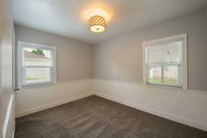 Empty room with dark carpet and baseboards