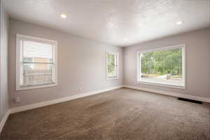 Carpeted empty room with baseboards, a textured ceiling, and recessed lighting