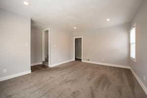 Carpeted empty room with stairs, recessed lighting, and baseboards
