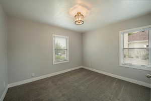 Spare room with baseboards and dark carpet