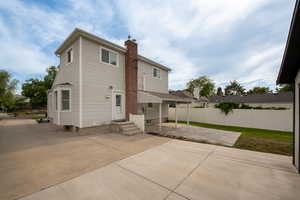 Rear view of property featuring a chimney and a patio area