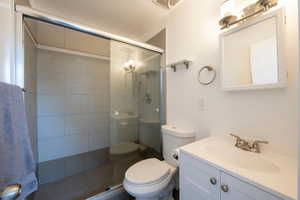 Full bath with toilet, a tile shower, and vanity