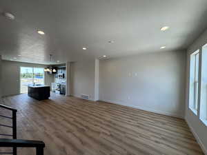 Unfurnished living room featuring a textured ceiling, wood finished floors, and recessed lighting