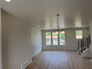 Unfurnished dining area with plenty of natural light, wood finished floors, a chandelier, stairs, and recessed lighting