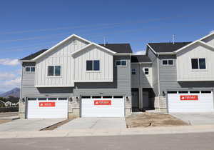 View of front of property with board and batten siding, an attached garage, driveway, and a mountain view