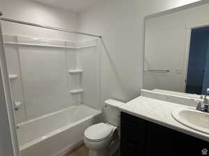 Bathroom featuring vanity, toilet, shower / bath combination, and wood finished floors