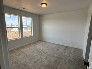 Carpeted spare room featuring baseboards and a textured ceiling