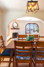Dining area featuring arched walkways, wood finished floors, a chandelier, and a fireplace with raised hearth