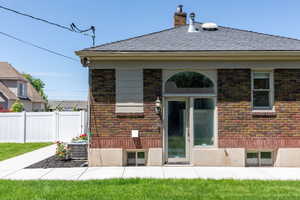 Back of property featuring cooling unit, brick siding, a chimney, and a shingled roof