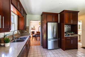 Kitchen with freestanding refrigerator, a sink, light tile patterned floors, and backsplash