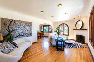 Living area featuring arched walkways, light wood finished floors, baseboards, and a fireplace