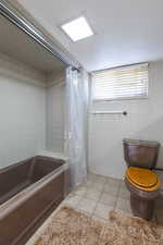Bathroom featuring tile walls, toilet, tile patterned floors, and shower / tub combo