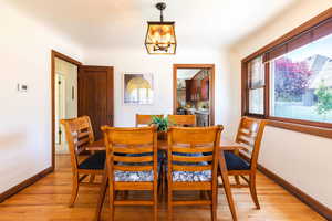 Dining area with a chandelier, light wood-style floors, and baseboards