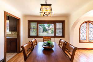 Dining room featuring arched walkways, light wood finished floors, a chandelier, and baseboards