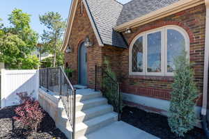Doorway to property with brick siding and roof with shingles