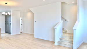Stairway with wood finished floors, a chandelier, baseboards, and recessed lighting