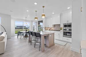 Kitchen featuring stainless steel appliances, tasteful backsplash, light countertops, a breakfast bar area, and baseboards