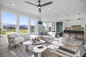 Living room featuring light wood-style flooring, recessed lighting, ceiling fan, a mountain view, and baseboards