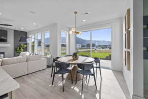Dining area featuring a mountain view, light wood-style floors, recessed lighting, a large fireplace, and ceiling fan