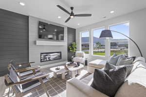 Living room with recessed lighting, a fireplace, a ceiling fan, wood walls, and wood finished floors