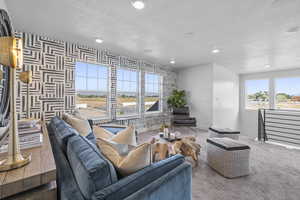 Living room featuring a textured ceiling, recessed lighting, carpet flooring, wallpapered walls, and baseboards