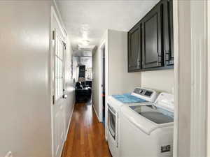 Laundry area with washer and dryer, cabinet space, dark wood-style flooring, a textured ceiling, and baseboards