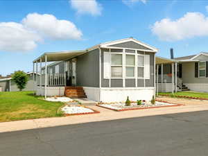 Manufactured / mobile home with a porch, an attached carport, a front lawn, and driveway