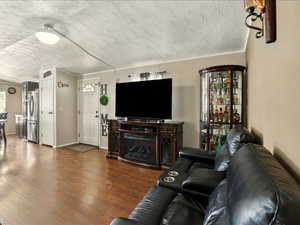Living area with a textured ceiling, wood finished floors, and ornamental molding