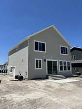 Back of house with stucco siding, entry steps, and central AC unit