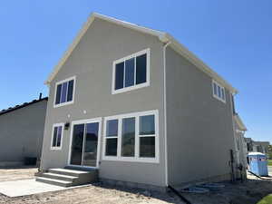 Rear view of house featuring cooling unit and stucco siding