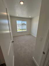 Carpeted spare room featuring baseboards, a textured ceiling, and recessed lighting