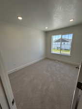 Empty room with recessed lighting, baseboards, carpet flooring, and a textured ceiling